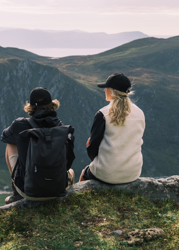 Eine Frau und ein Mann sitzen auf einem Bergvorsprung und schauen in die Ferne