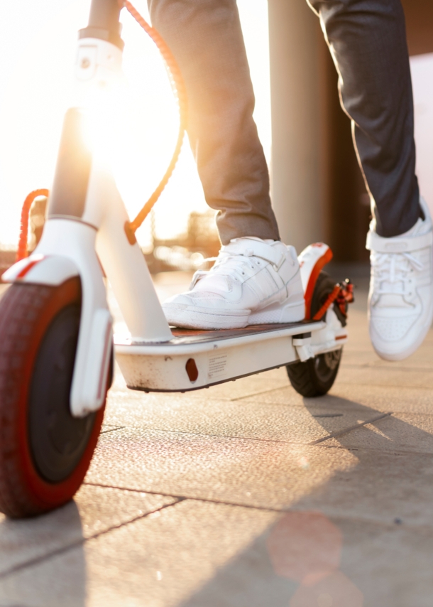 Nachaufnahme eines Rollers, auf dem ein Mann mit weißen Turnschuhen steht, Symbolbild