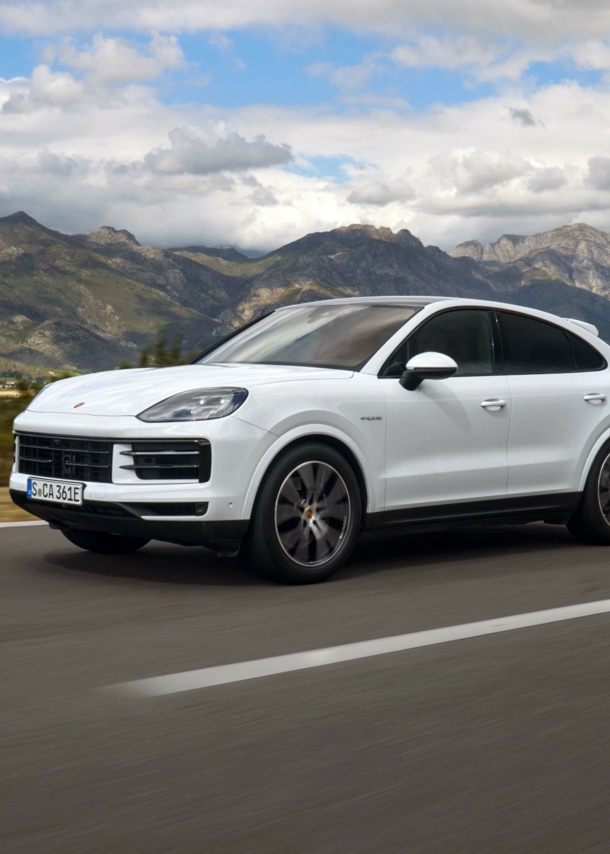 Ein weißer Porsche Cayenne auf einer Straße, im Hintergrund Berge