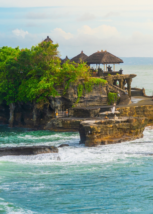 Ein Tempel und mehrere Bäume auf einem Felsen im Meer