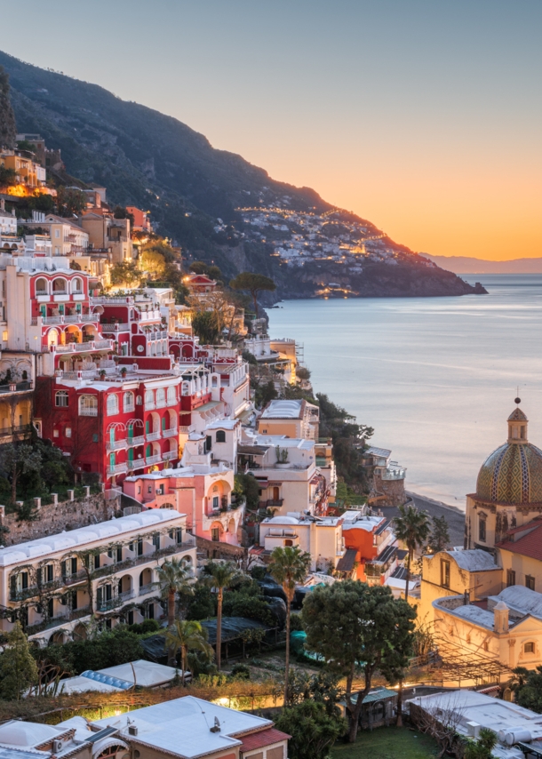 Das Dorf Positano am Hang eines gebirgigen Küstenabschnittes bei Sonnenuntergang