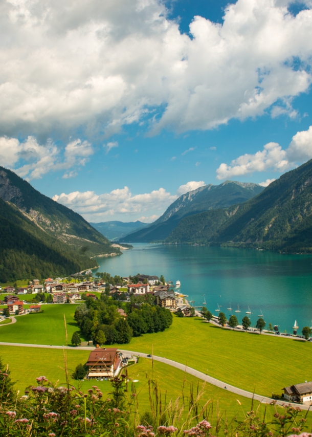 Ein türkisfarbener See zwischen Bergen und einem kleinen Dorf