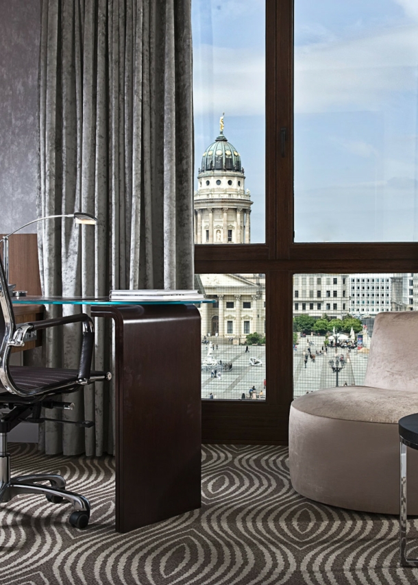 Luxuriöses Hotelzimmer mit Schreibtisch an einem bodentiefen Fenster mit Blick auf den Dom am Gendarmenmarkt in Berlin.