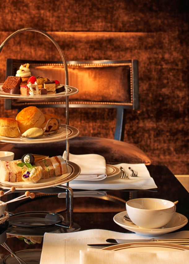 Eingedeckter Tisch zur Teatime mit Gebäck und Süßspeisen auf einer Etagere.