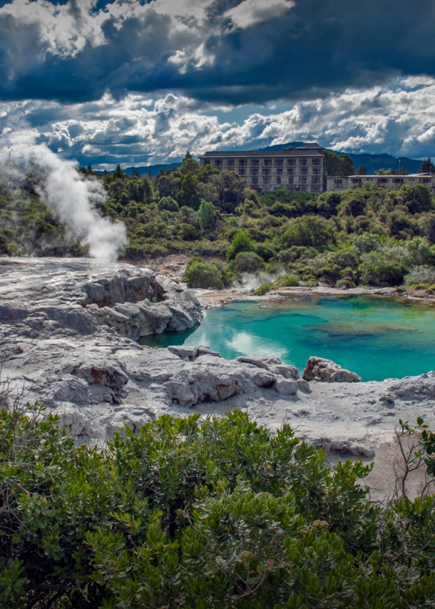 Blick auf Landschaft mit dampfenden Geysiren und grünblauem Wasser