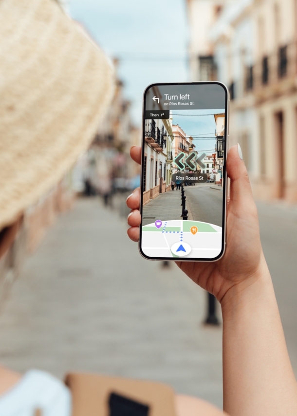 Eine Frau navigiert mit Blick auf ihr Smartphone per Live View von Google Maps durch eine Straße.