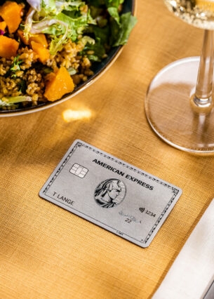 Eine Amex Platinum Card liegt auf einem gedeckten Tisch in einem gehobenen Restaurant