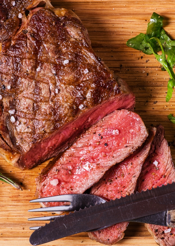 Aufsicht eines gebratenen, angeschnittenen Steaks auf einem Holzbrett.