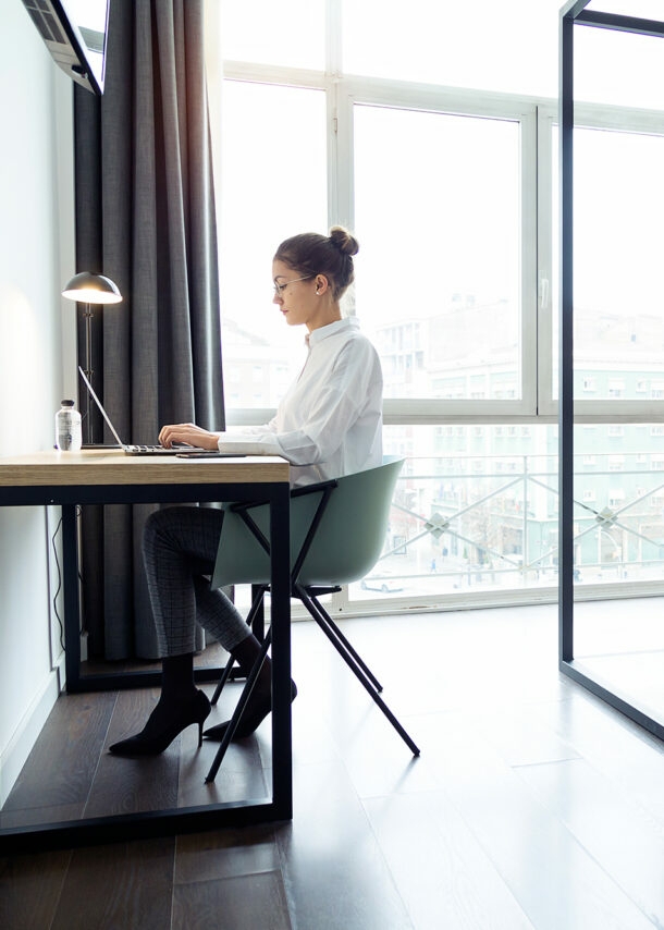 Junge Geschäftsfrau arbeitet am Laptop in ihrem Hotelzimmer