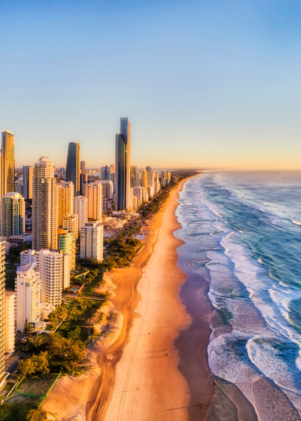 Luftaufnahme der Skyline von Surfers Paradise am kilometerlangen Sandstrand bei goldenem Sonnenlicht.