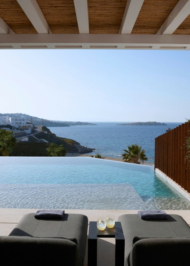 Terrasse mit Liegen und Infinitypool mit Meerblick an einem Küstenort.