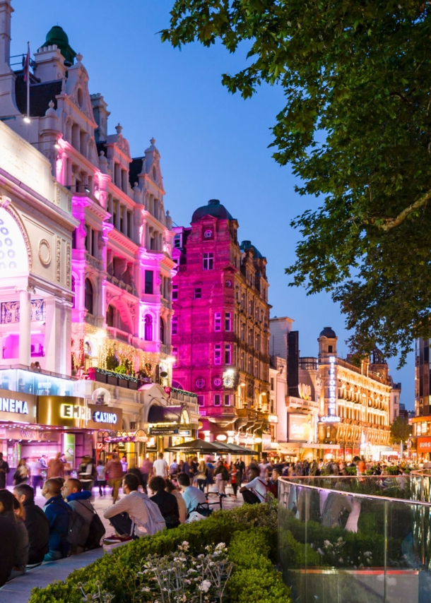 Belebter Leicester Square mit beleuchteter Häuserfassade am Abend.