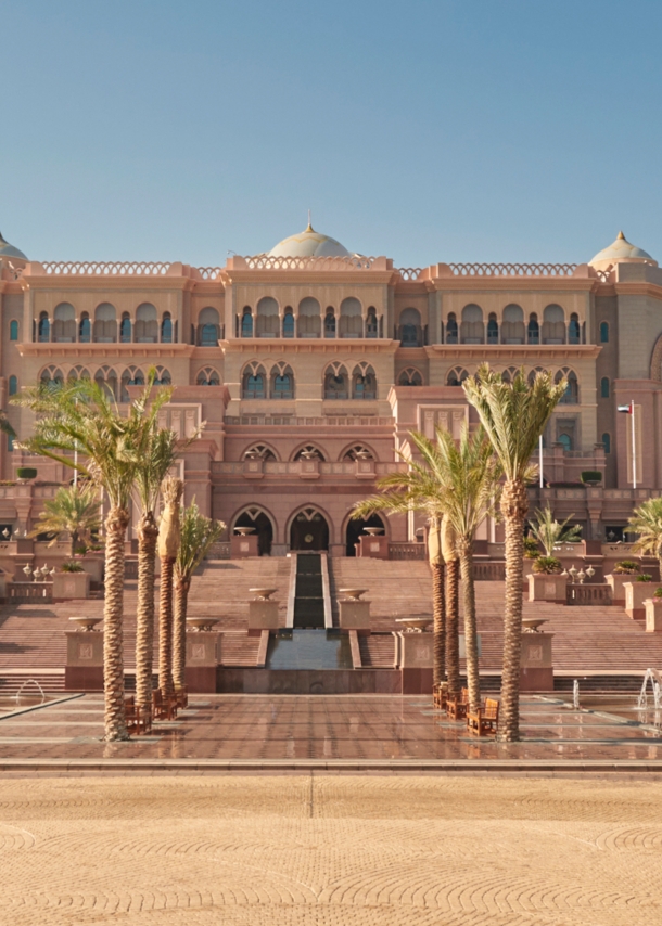 Außenansicht des Emirates Palace Mandarin Oriental Hotels in Abu Dhabi mit Palmen und Brunnen im Vordergrund.