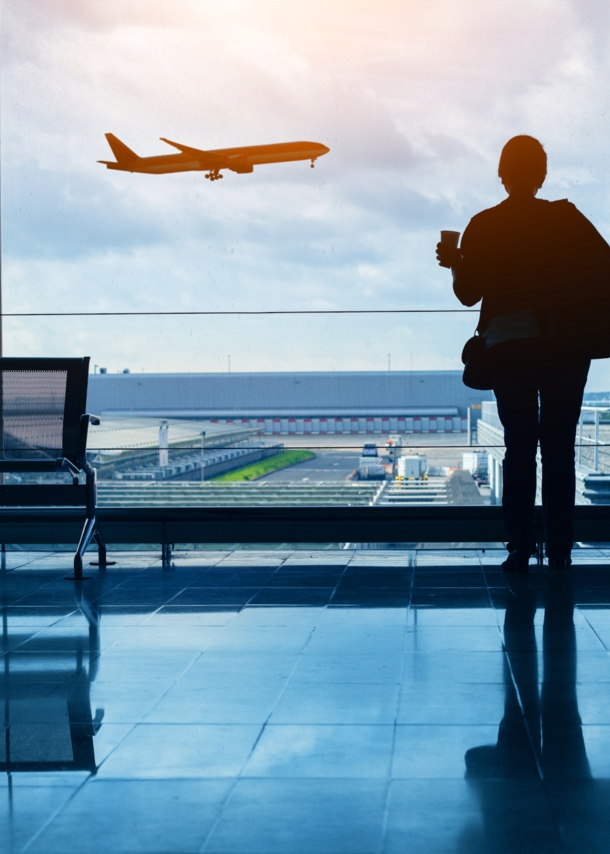 Silhouette einer Frau am Flughafen, die den Start eines Flugzeugs beobachtet.