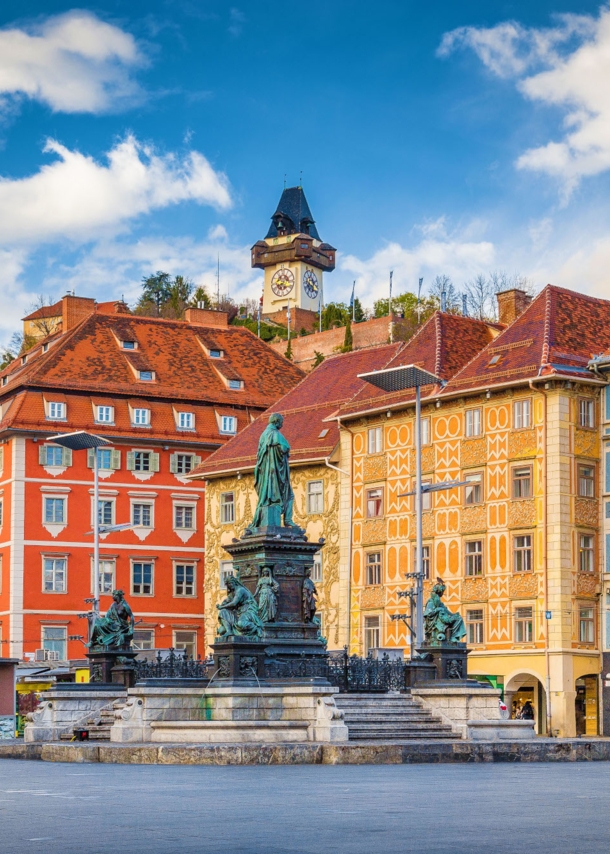 Marktplatz mit Brunnen vor bunter Häuserfassade in der Altstadt von Graz.