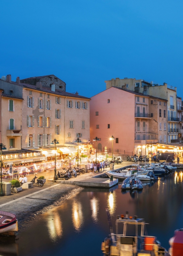 Beleuchtete Restaurants am Hafen von Saint Tropez am Abend.