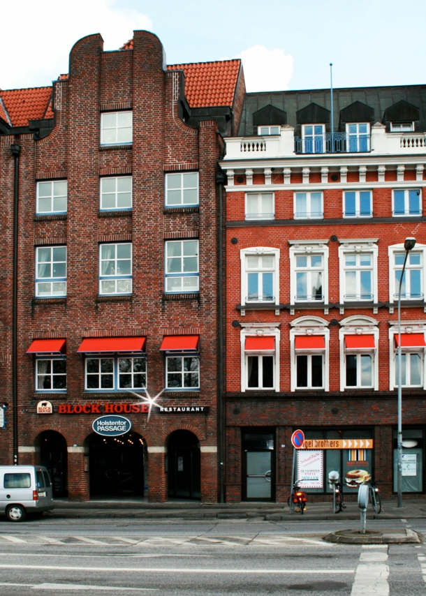 Häuserfront mit Giebelhäusern aus Rotsteinklinker mit Block House Schriftzug.