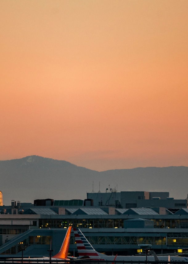 Tower des Vancouver Airports bei Sonnenuntergang und ein startendes Flugzeug.