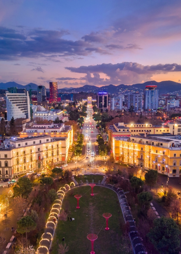 Beleuchtetes Stadtpanorama von Tirana bei Abenddämmerung aus der Luftperspektive.