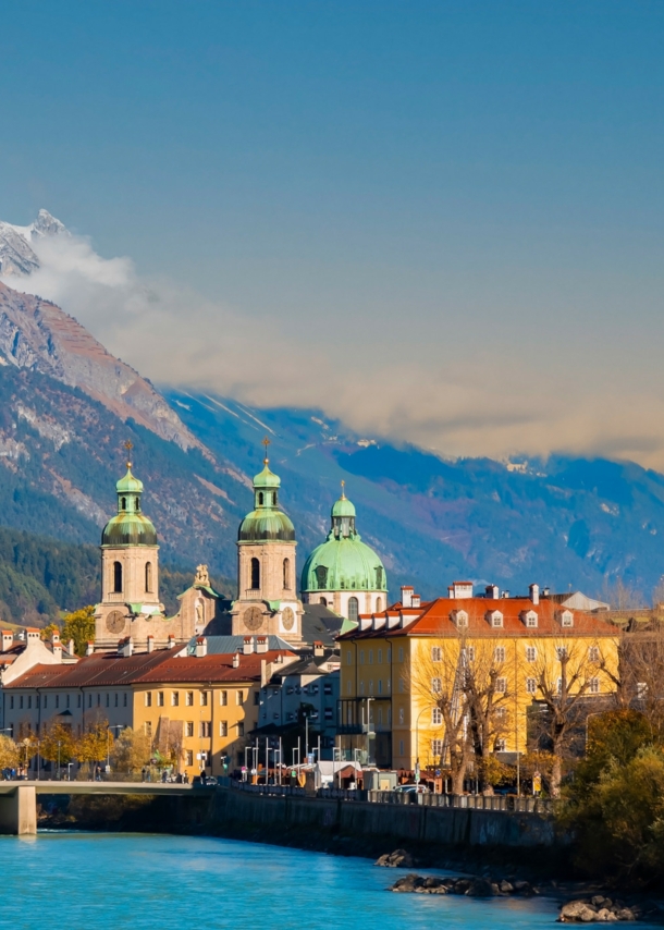 Skyline der Innsbrucker Altstadt am Fluss vor Bergpanorama.