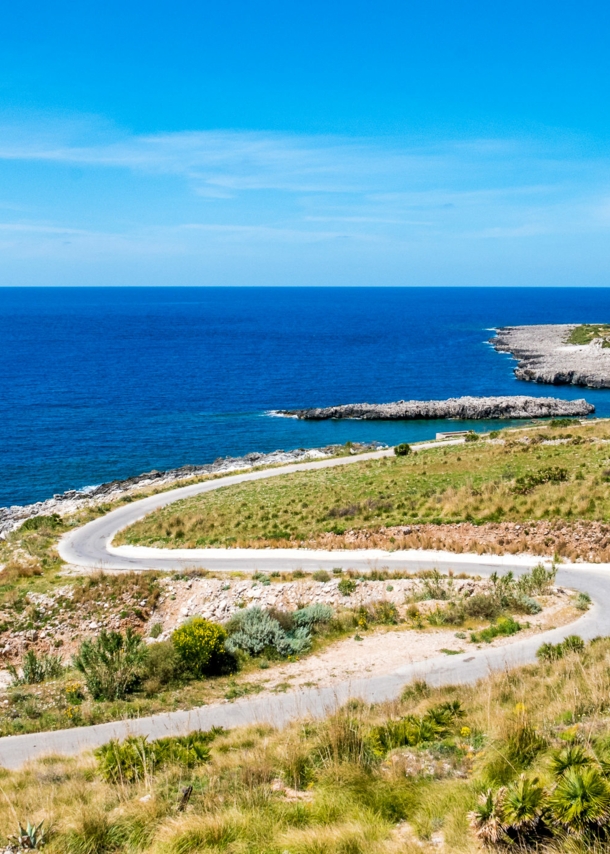 Kurvige Küstenstraße in mediterraner Landschaft.