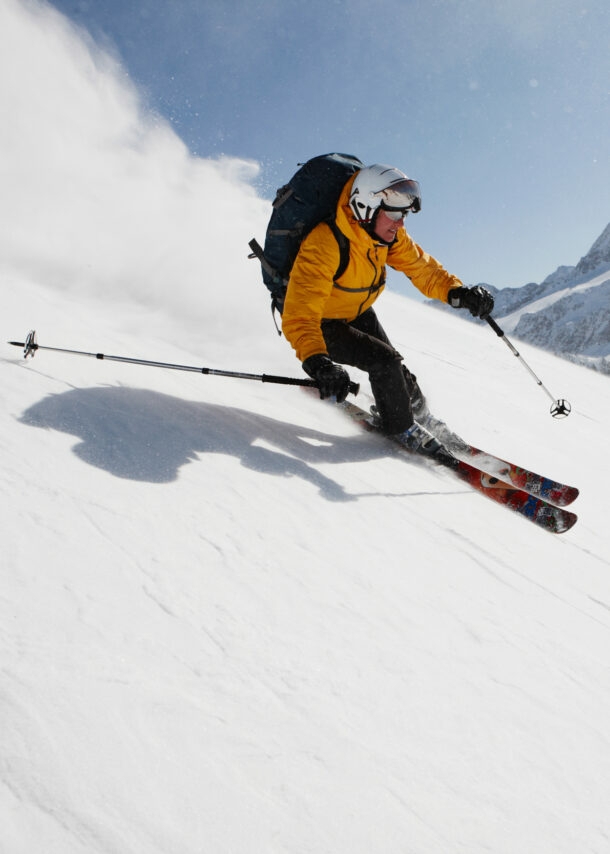 Eine skifahrende Person auf einer Piste vor Bergpanorama.