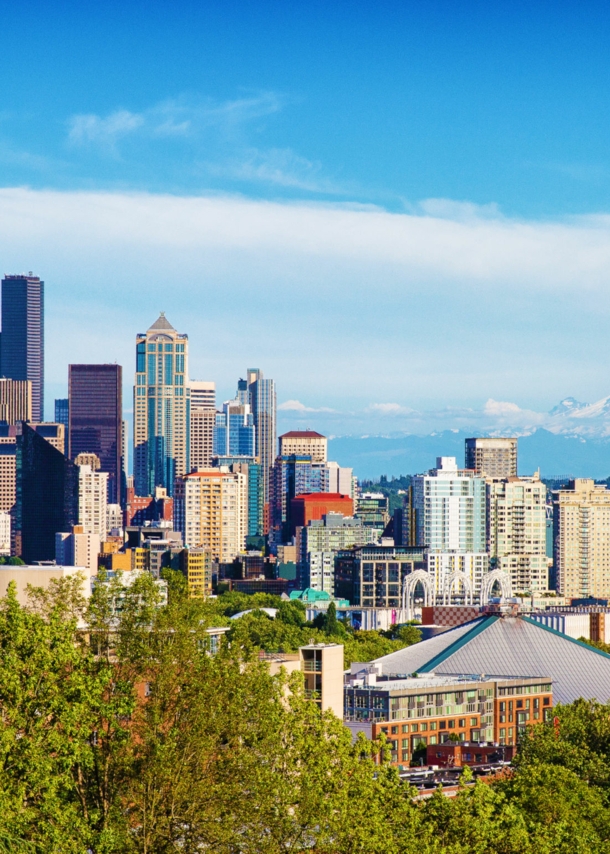 Skyline von Seattle mit Space Needle Turm vor schneebedeckter Bergspitze am Horizont.