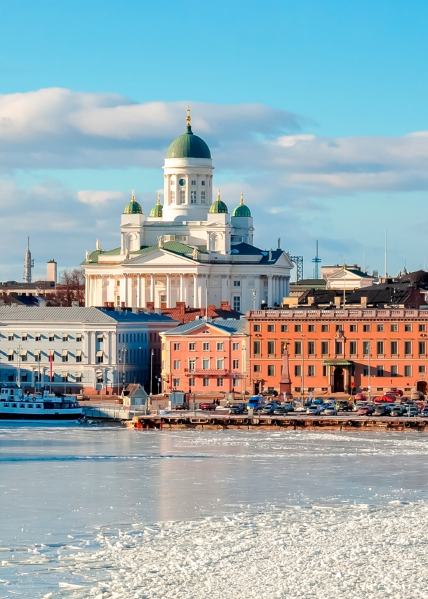 Stadtpanorama von Helsinki mit Dom an einer zugefrorenen Wasserfläche im Vordergrund.