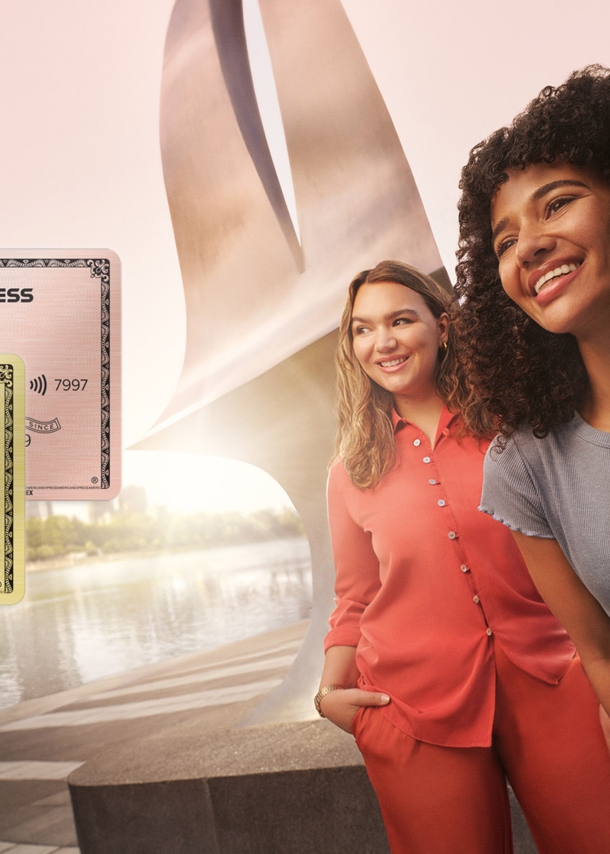 Zwei junge Frauen stehen lächelnd auf einem Platz mit modernen Gebäuden im Hintergrund, als Collage im Vordergrund eine American Express Gold Card und Gold Card Rosé.
