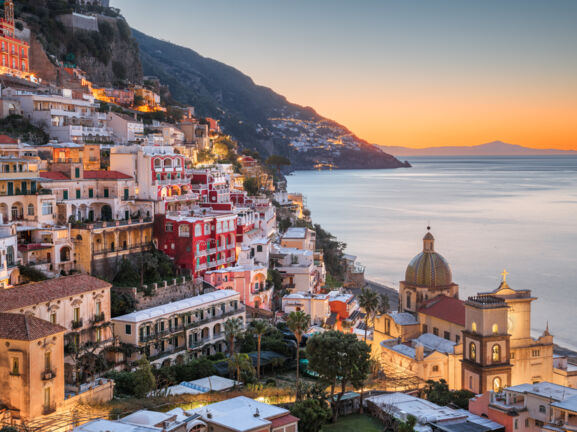 Das Dorf Positano am Hang eines gebirgigen Küstenabschnittes bei Sonnenuntergang