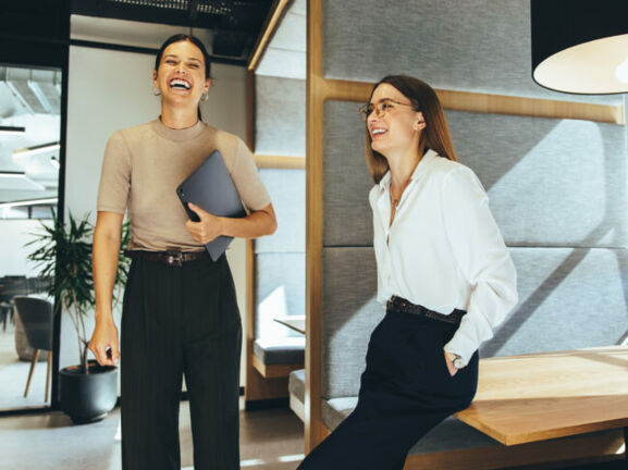 Zwei junge Geschäftsfrauen lachen im Büro