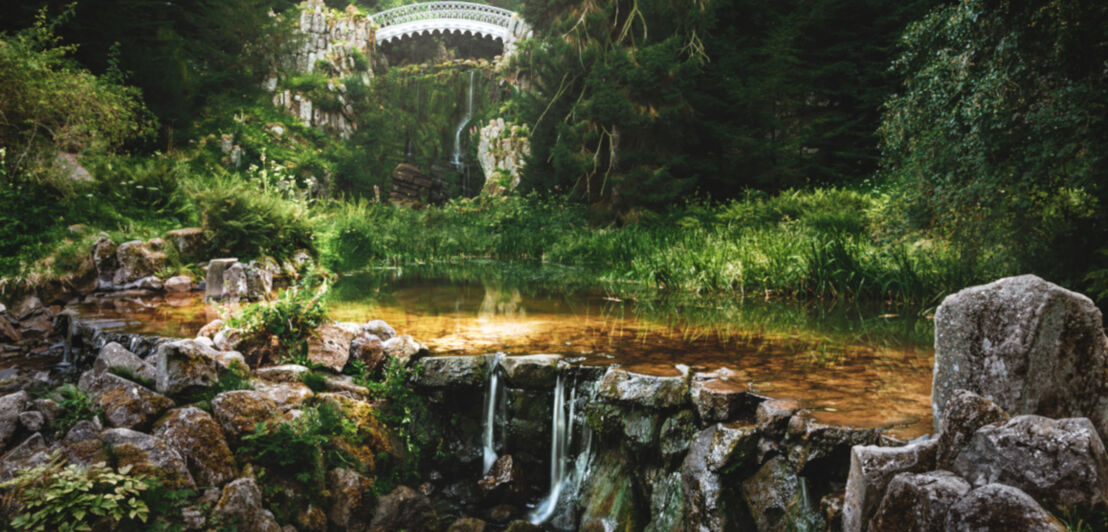 Ein verwunschener Teich mit einer filigranen Brücke im Hintergrund