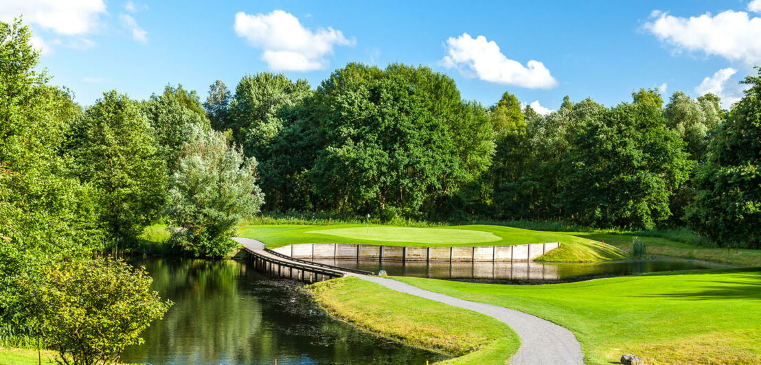 Ein Weg führt über eine kleine Brücke über einen Teich