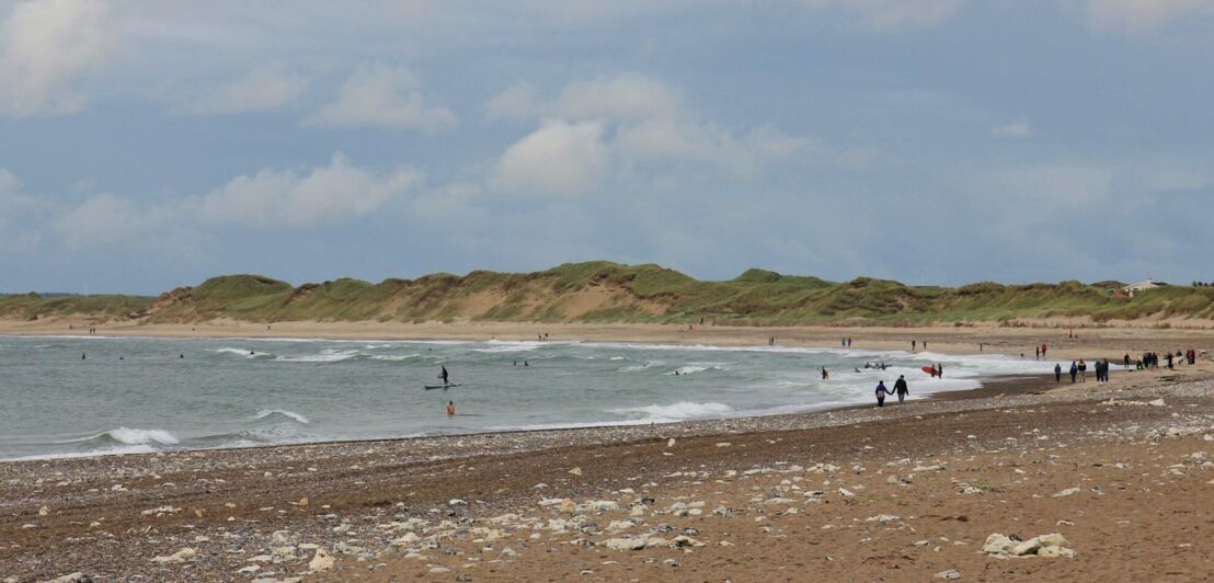 Ein Strand mit Spaziergängern und Surfern