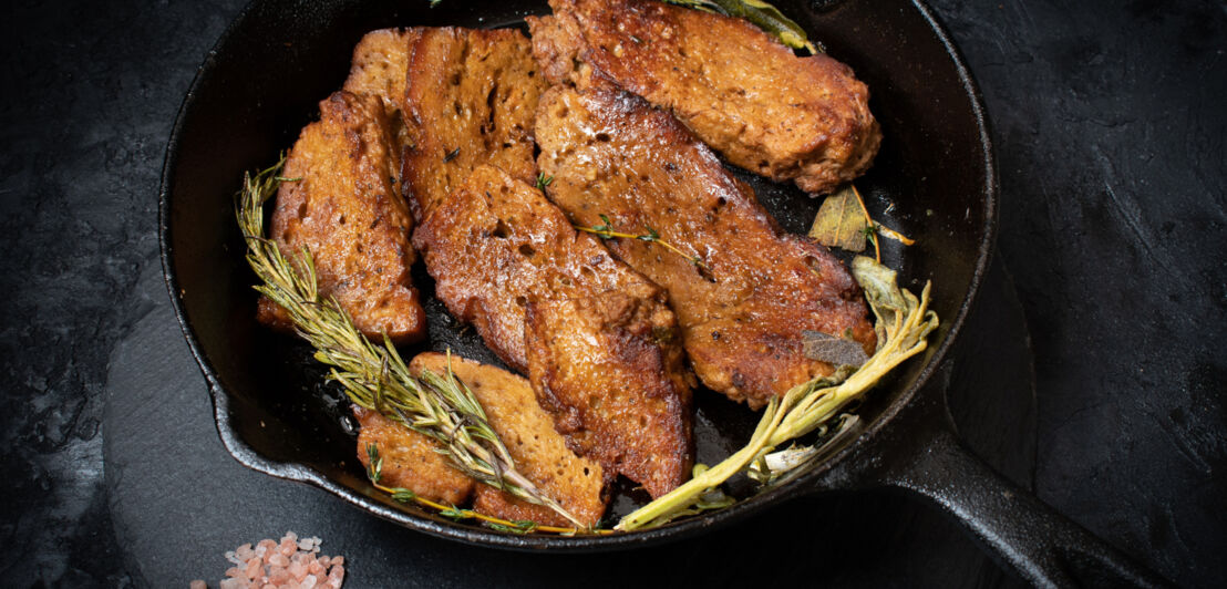 Eine Pfanne mit Steaks aus Seitan und Rosmarinzweigen