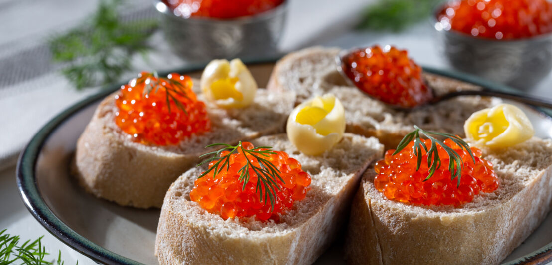 Rote Fischeier und daneben Butterstückchen auf Baguettescheiben