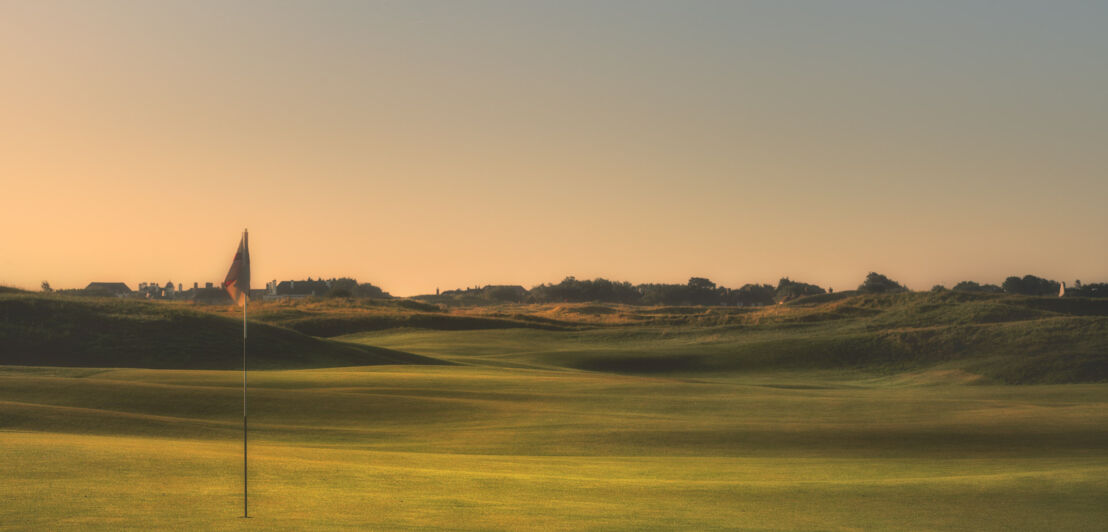 Eine Fahne in einem Golfloch auf einem gepflegten Green