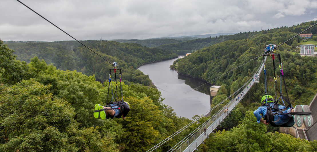 Zwei Zipliner überqueren an Stahlseilen die Rappbodetalsperre