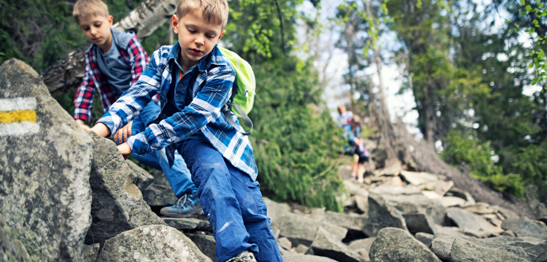 Kinder klettern einen steinigen und felsigen Hang entlang