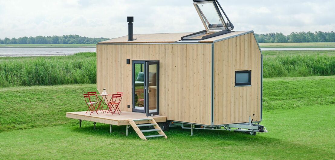 Ein helles Tiny House auf Rädern steht direkt an der Nordsee