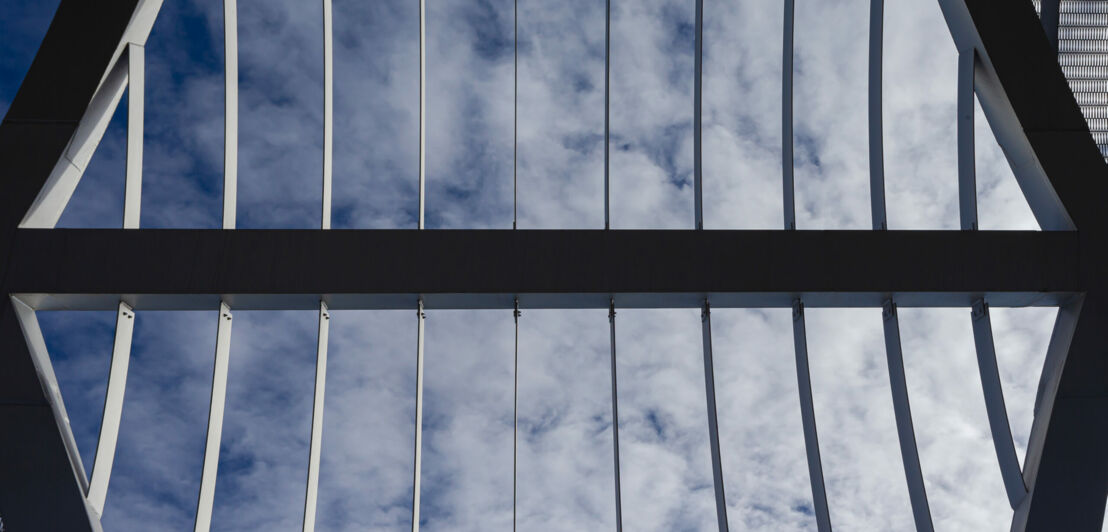 Abstraktes Foto paralleler Metallverstrebungen vor bewölktem Himmel