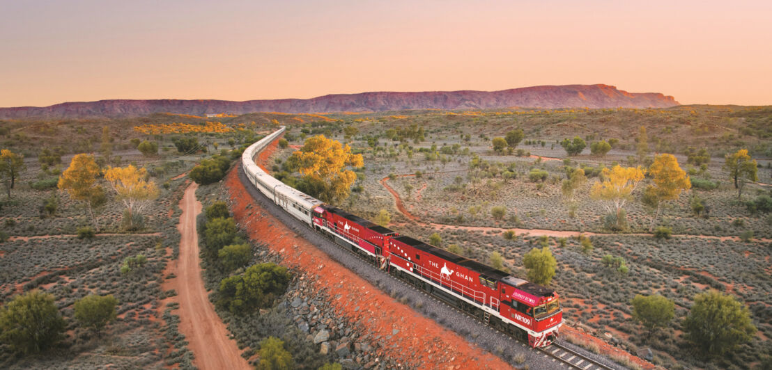 Panoramaaufnahme eines Zuges, der durch das australische Hinterland in der Dämmerung fährt