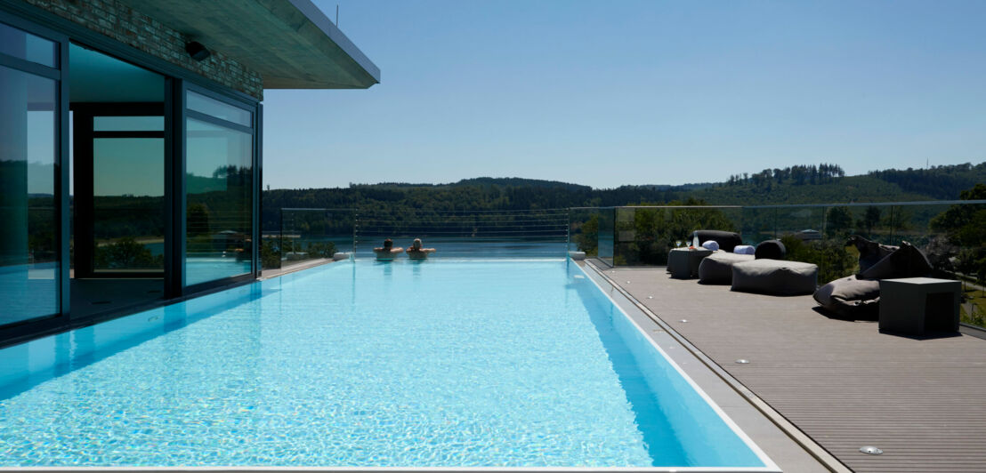 Infinitypool auf dem Dach eines Hotels, im Wasser zwei Personen, die in die Natur schauen