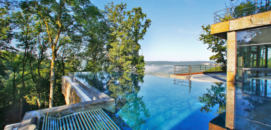 Rooftop-Pool eines modernen Hotels, im Hintergrund Baumkronen