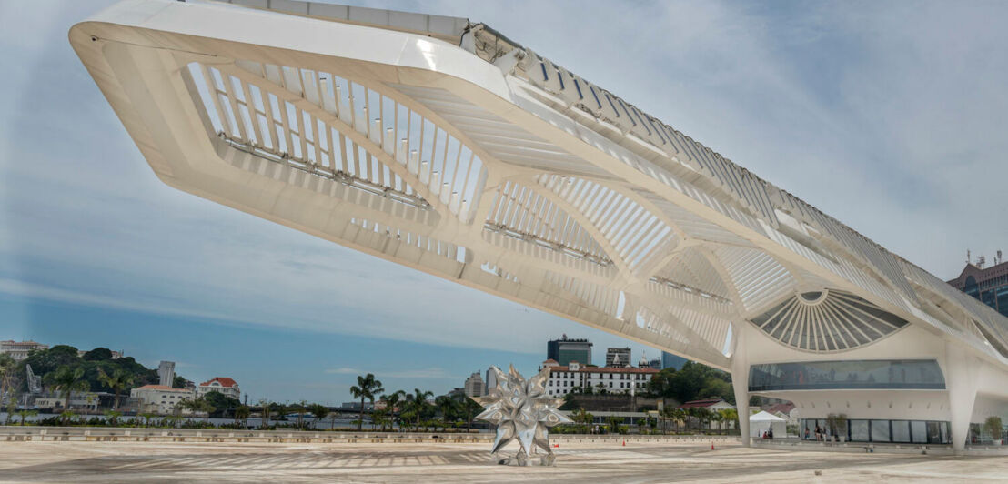 Weißes, futuristisches Gebäude eines Museums mit ausladender Architektur auf einem Vorplatz