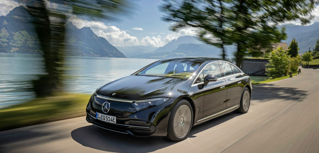 Ein dunkler E-Mercedes auf der Straße vor einer alpinen Kulisse.