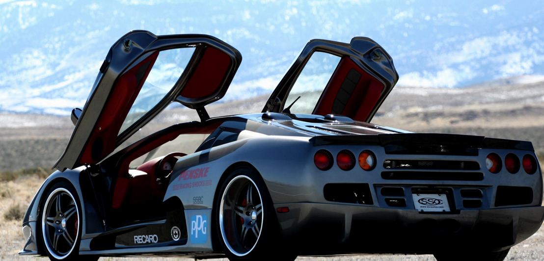 Der SSC Ultimate Aero TT mit offenen Flügeltüren, im Hintergrund eine Landschaft.