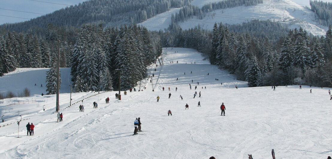 Skifahrer auf einer breiten Piste mit Schlepplift