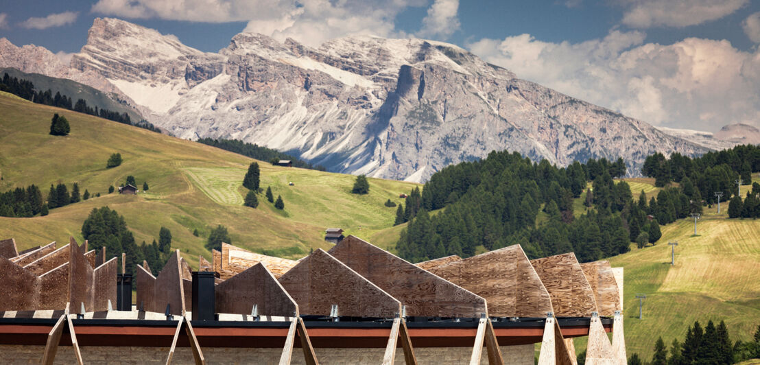 Teil des Chalets vor dem Hintergrund der grünen Al und schneebedeckten Dolomiten