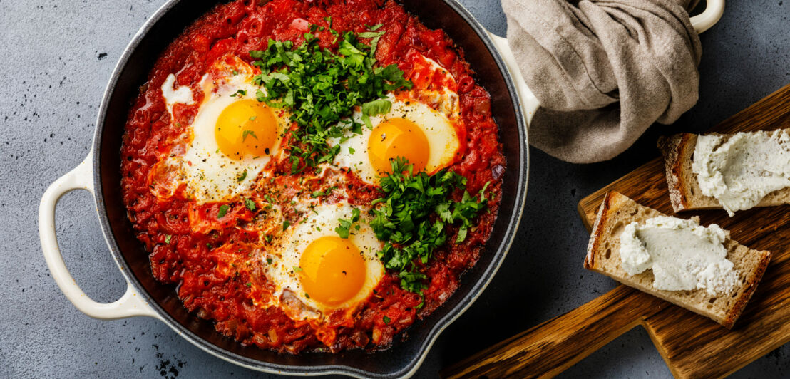 Das herzhafte Frühstück Shakshuka ist garniert mit drei Spiegeleiern.